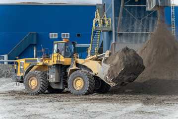 A loader with a full bucket stands near the filtration shop waiting to start loading.