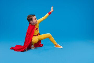 Superhero child waving hand in studio