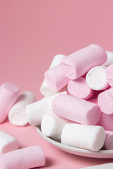 Marshmallows on a pink background. Colored marshmallows on a white plate. Delicate dessert