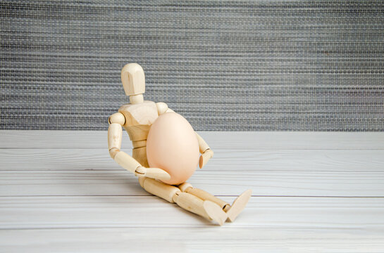 wooden figurine of man holding egg. mannequin with an egg. Creative image. Space for text