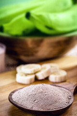 spoon with banana flour and fruits in the background, point focus. Alternative and homemade flour