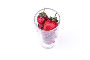 Fresh strawberry in glass cup on white background. Summer refreshing juice creative concept.