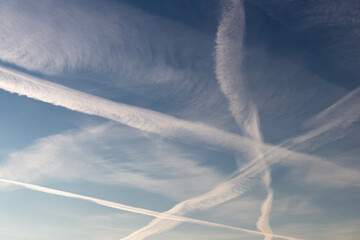 Chmury kondensacyjne po przelocie samolotu na błękitnym niebie. - obrazy, fototapety, plakaty