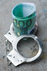 a pack of one hundred euro banknotes in handcuffs