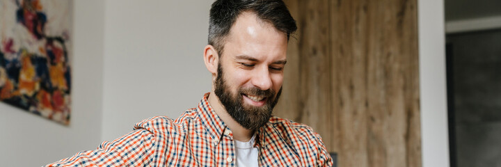 Obraz premium Smiling brunette bearded man holding mobile phone