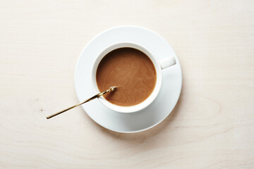 Cup of coffee with cream on a wooden table.