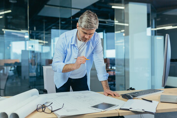 An experienced architect working on a drawing, a man in a modern office at the computer, a designer draws a modern project