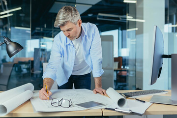 An experienced architect working on a drawing, a man in a modern office at the computer, a designer draws a modern project