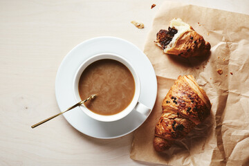 Cup of coffee with cream and chocolate croissant.