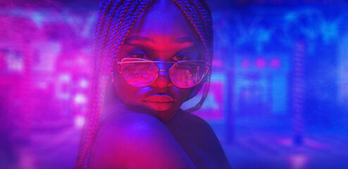Portrait of fashion young girl in sunglasses in red and blue neon light in the studio