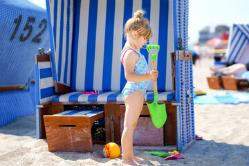 Little preschool girl playing with sand toys on the beach. Cute happy toddler child on family...