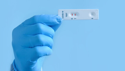 A doctor or nurse wearing a gloves shows a rapid laboratory test for COVID-19 to detect IgM and IgG antibodies to the new coronavirus. The test shows a positive result.Copy space.