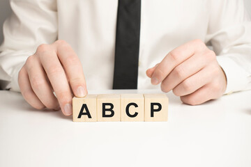 Closeup man add more some alphabets wood cubes into the row to complete the word abcp, converge benefits, mutal benefits concept