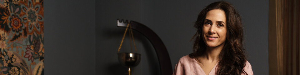 Brunette happy woman wearing robe smiling at camera in spa indoors