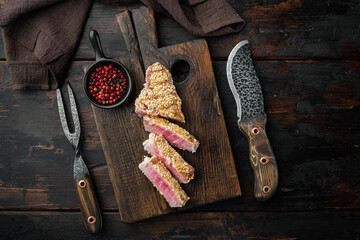 Grilled Ahi Tuna Steak, on wooden serving board, on old dark  wooden table background, top view flat lay