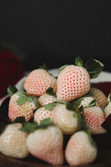 Moody Valentine Still Life Vertical. Close Up Pineberry on Wooden Plate with Dark Background. White Strawberry. Dark Valentine Aesthetic. Strawberries and Wine.
