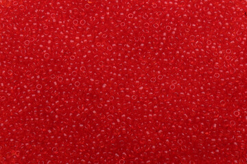 Bright red glass beads as background, top view