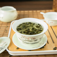 Gaivan and chahay with green tea  
 and tea brew on a brown background. Tea ceremony.  Traditional chinese tea utensils. 