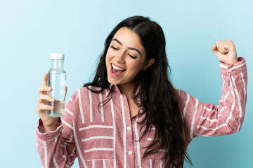 Young woman with a water isolated on blue background celebrating a victory