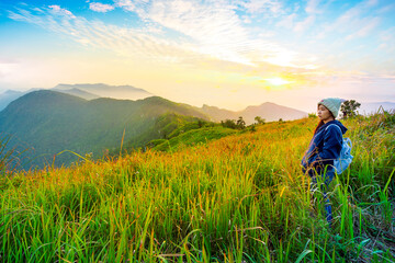 Naklejka na ściany i meble Tourist woman standing on peak of mountains and enjoy view with beautiful mist and sunrise from her success at Gunungsilepat mountains, Yala province south of Thailand 