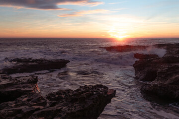 Beautiful sunrise at the coast early morning with waves crashing onto the rocks 