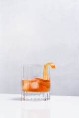 Vaso de vermut con hielo decorado con cerezas y rodajas de naranja sobre mesa blanca