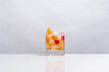 Vaso de vermut con hielo decorado con cerezas y rodajas de naranja sobre mesa blanca - obrazy, fototapety, plakaty
