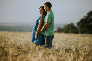 Naklejka na ściany i meble Young husband and his pregnant wife in the summer field