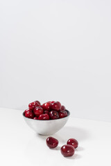 Cerezas dulces rojas en un recipiente de plata y fondo blanco