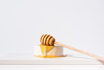 Verter la miel sobre el queso de cabra, con gotero de madera. Aperitivo comida mediterránea sobre...