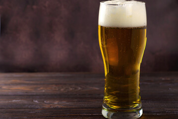 a large glass of cold light beer with foam on a dark background. St.Patrick 's Day