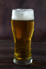 a large glass of cold light beer with foam on a dark background. St.Patrick 's Day