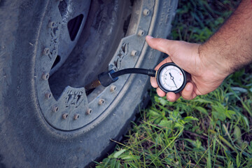 Close-up of a man checking and measuring tire pressure. Preparing a four-wheel drive offroad...