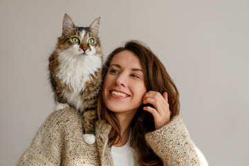 Portrait of young woman holding her siberian cat with green eyes. Female and cute long hair kitty...
