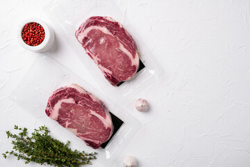 Premium rib eye steak in a vacuum pack, on white stone table background, top view flat lay, with copy space for text