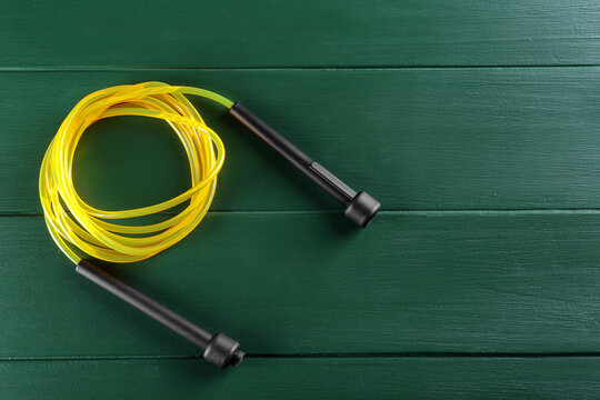 Skipping rope on green wooden table, top view. Space for text