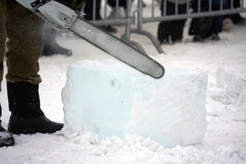 Saws an ice cube with an electric saw to decorate ice sculptures