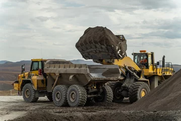 Fotobehang Vrachtwagen A loader loads ore into an articulated dump truck.  © CjVitoS