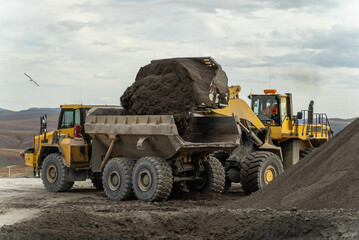 The loader loads an articulated dump truck. The action takes place near the filtration shop.