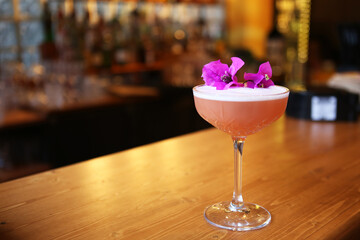 Pink cocktail with flowers on the table.