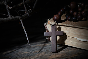 Close up rosary, ancient Bible and thorn wreath as symbol of death and resurrection of Jesus Christ.