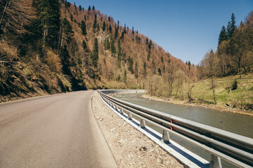 Fototapeta premium Mountain road trouble river, mixed forest and fence
