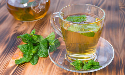 Glass cup of tea with mint on the table. Image with selective focus