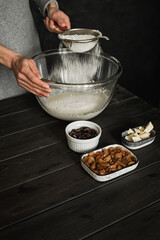 Baking sweet cottage cheese braided bread with raisins and jam. Ingredients on a wooden table. Adding flour into a big bowl. Lifestyle image.