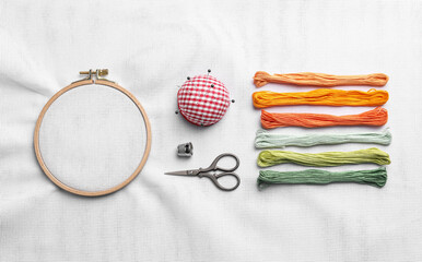 Flat lay composition with threads and embroidery hoop on white fabric - obrazy, fototapety, plakaty