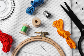 Embroidery hoop and other accessories on white fabric, flat lay © New Africa