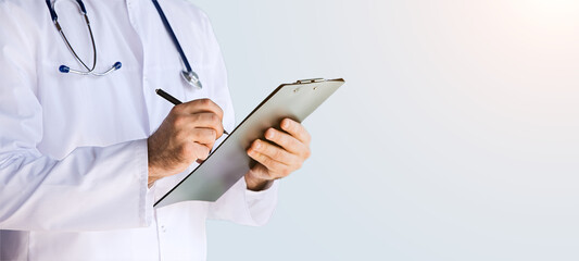 Healthcare, medicine concept: Portrait handsome doctor writing about diagnosis on clipboard...