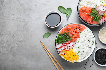 Delicious poke bowls with salmon and vegetables served on light grey table, flat lay. Space for text