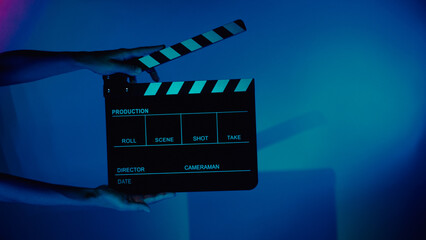 Blurry images of movie slate or clapper board. Hand holds empty film making clapperboard on color background in studio for film movie shooting or recording. Film slate for Youtuber video production. © gnepphoto
