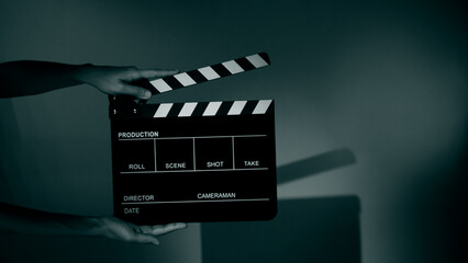 Blurry images of movie slate or clapper board. Hand holds empty film making clapperboard on color...